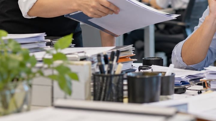 Chồng giấy tờ trên bàn làm việc chờ xuất kết quả