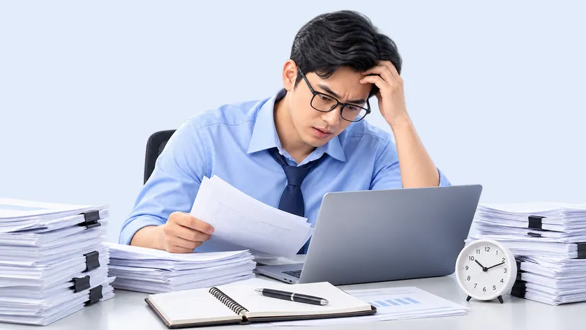 Nhân viên ngồi giữa những chồng tài liệu giấy chất cao